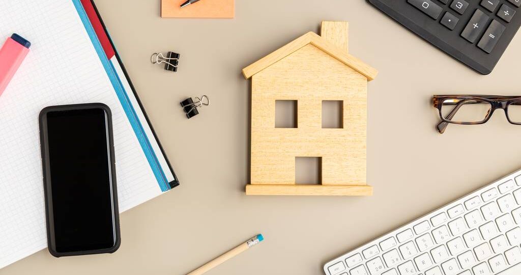 Work at home concept. Desk with house icon, smart phone, keyboard and office supplies