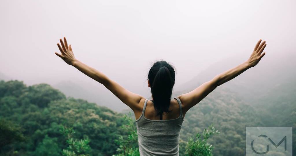 Happy woman with outstretched arms enjoying the view on morning mountain valley