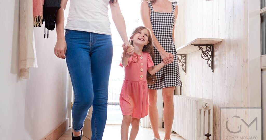 View Inside Hallway As Same Sex Female Couple With Daughter Open Front Door Of Home